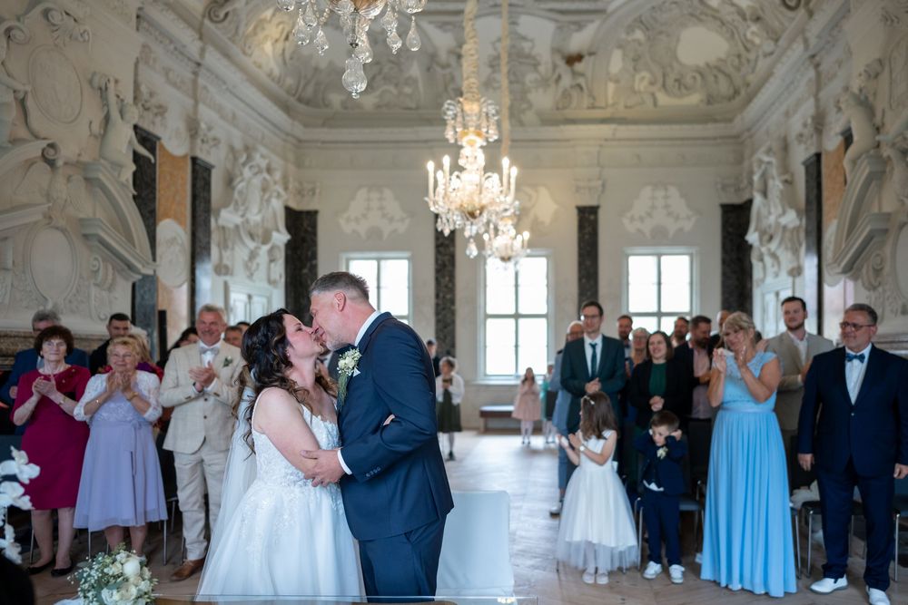 Brautpaar küsst sich im Saal, Familie schaut zu, emotionale Szene, Schloss Mirow