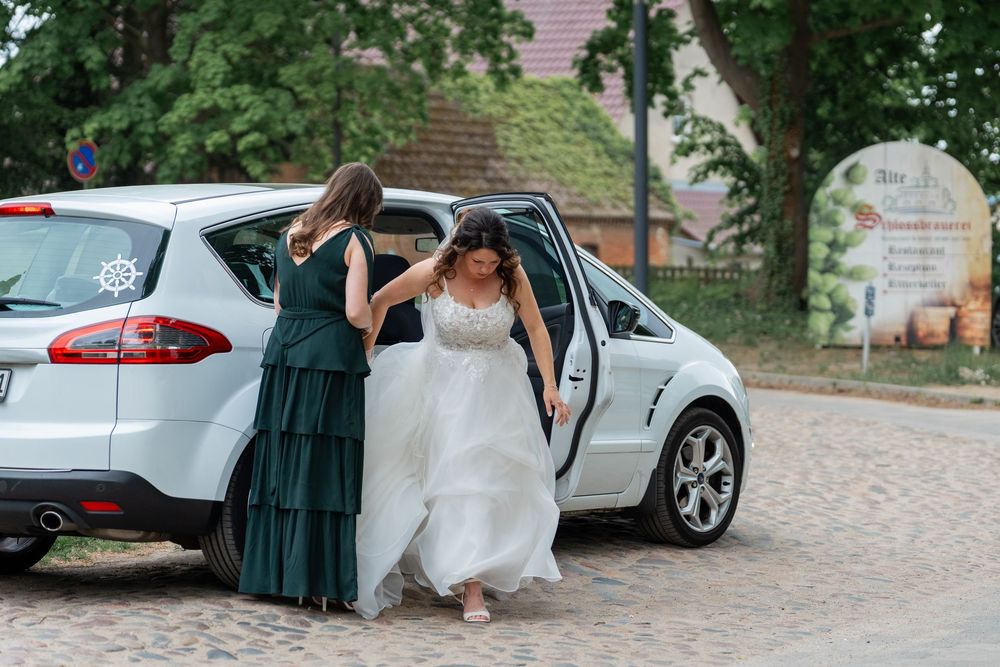 Braut steigt mit Helferinnen ins Auto ein, Rückansicht, Schloss Mirow