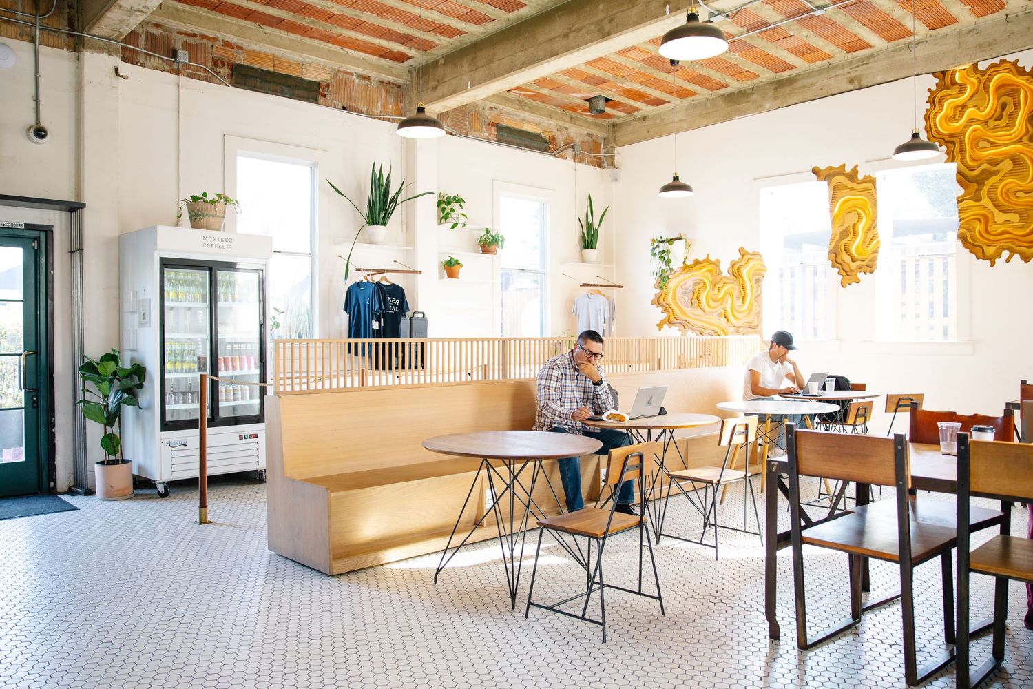 Spacious industrial-style interior with exposed beam ceiling and white tile floors.