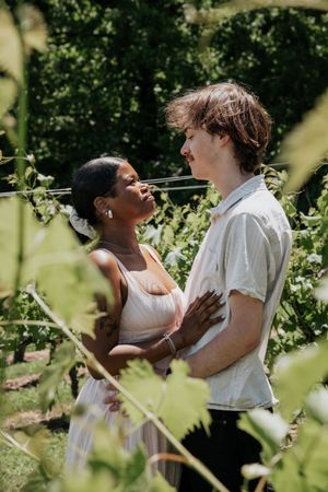 A loving couple embraces in a sunny vineyard on a summer day.