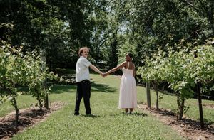 A couple dances together in a lush garden setting surrounded by greenery.