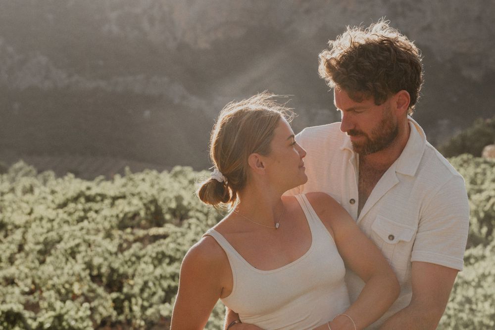 An intimate moment captured between a couple in warm sunlight with mountains in the background.