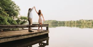 Long wooden pier stretches over calm lake waters with couple at the end.