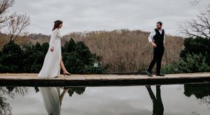 A dramatic wedding photo of a couple standing on opposite ends of a reflective pool.