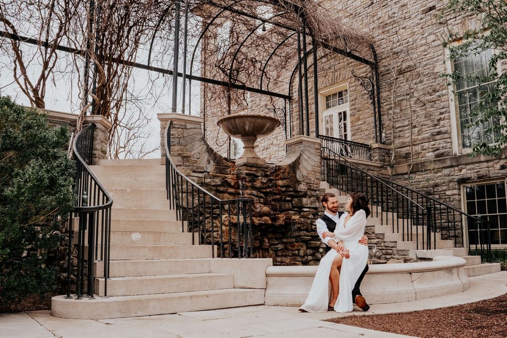 A wedding couple shares an intimate moment on stone steps of a historic building.