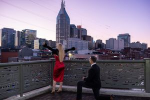 Nashville skyline at sunset with buildings silhouetted against purple sky.