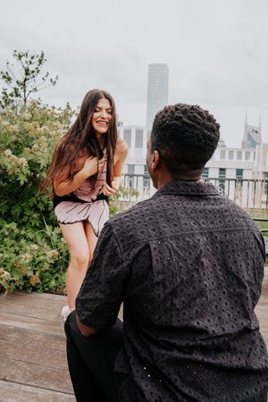 A joyful moment captured on an urban rooftop deck with greenery and skyscrapers in the background.