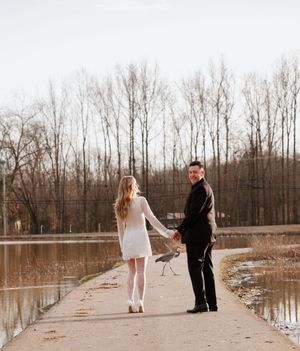 Two figures walking along a flooded path near bare winter trees.
