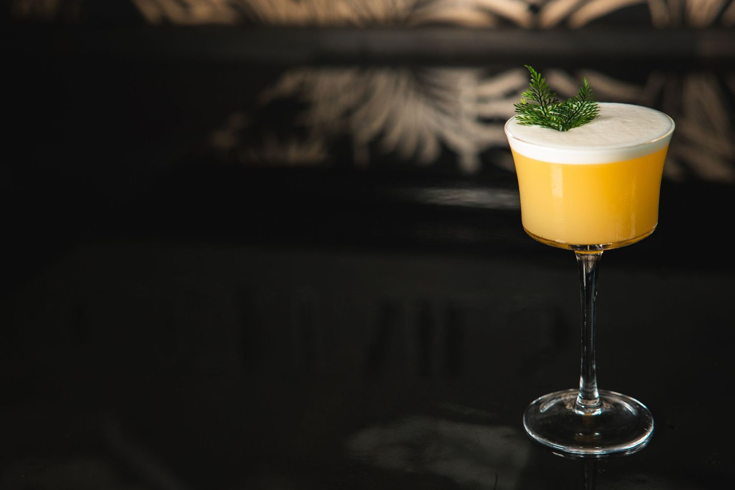 Elegant cocktails garnished with herbs on a dark wooden surface.