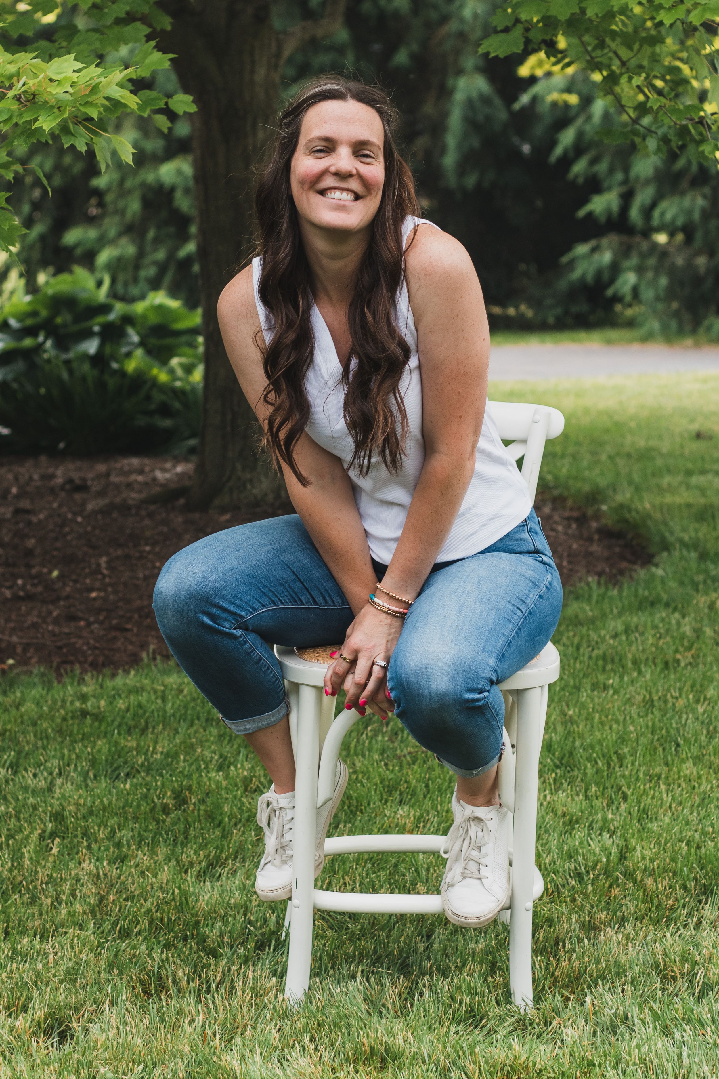 Woman sitting on a stool with a big smile. Self-portrait of Sam an affordable lifestyle family photographer in South Lyon, Michigan.