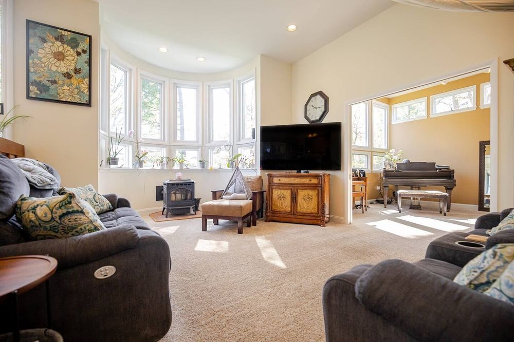 Living room with TV, large sunlit windows, and carpet in Catonsville, Maryland. Real estate photography by Photograph Maryland.