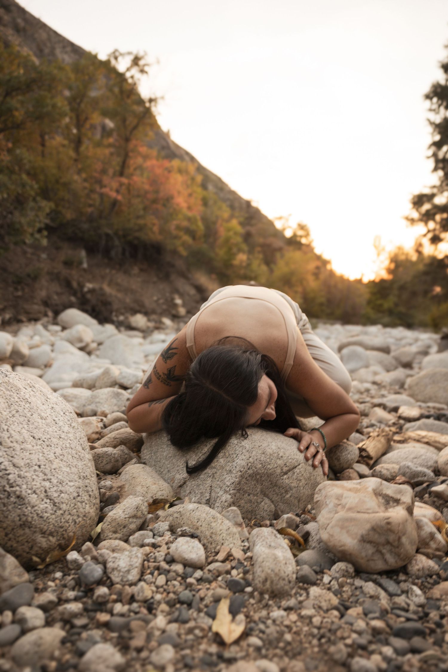 Woman hugging rocks in golden hour lighting, embodying grounded energy of the landscape itself.