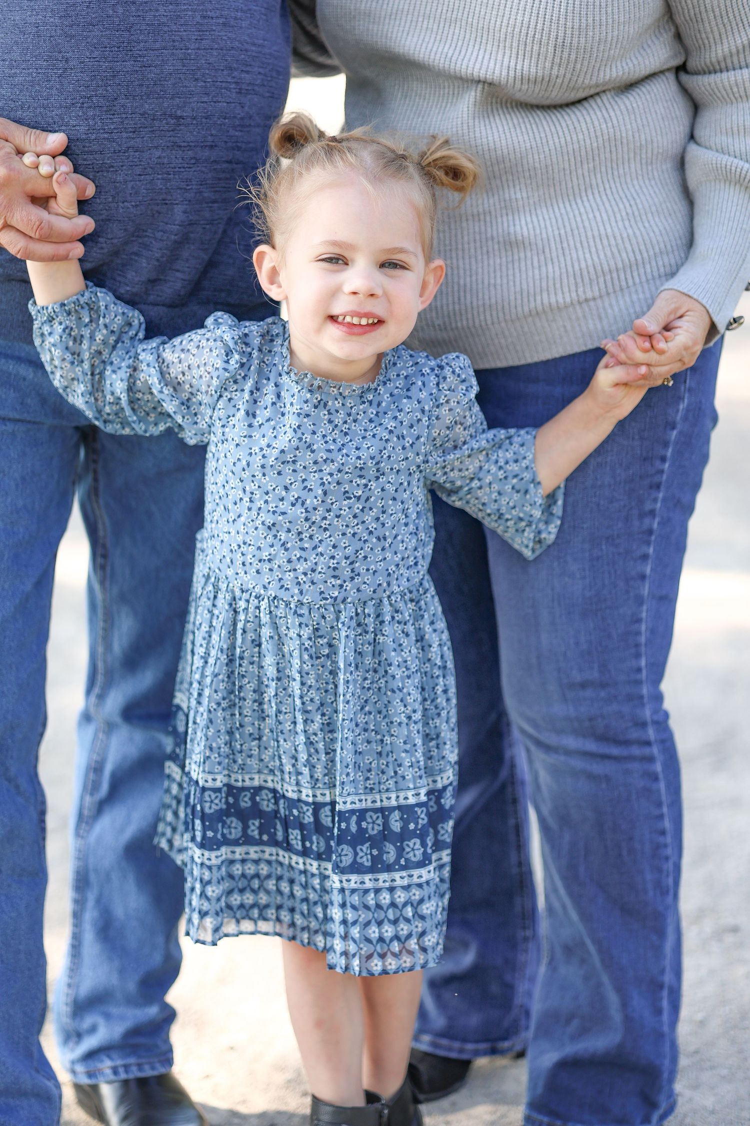 Springfield, IL family photographer captures a girl smiling while holding her grandparents hands during a photo session in Central, IL