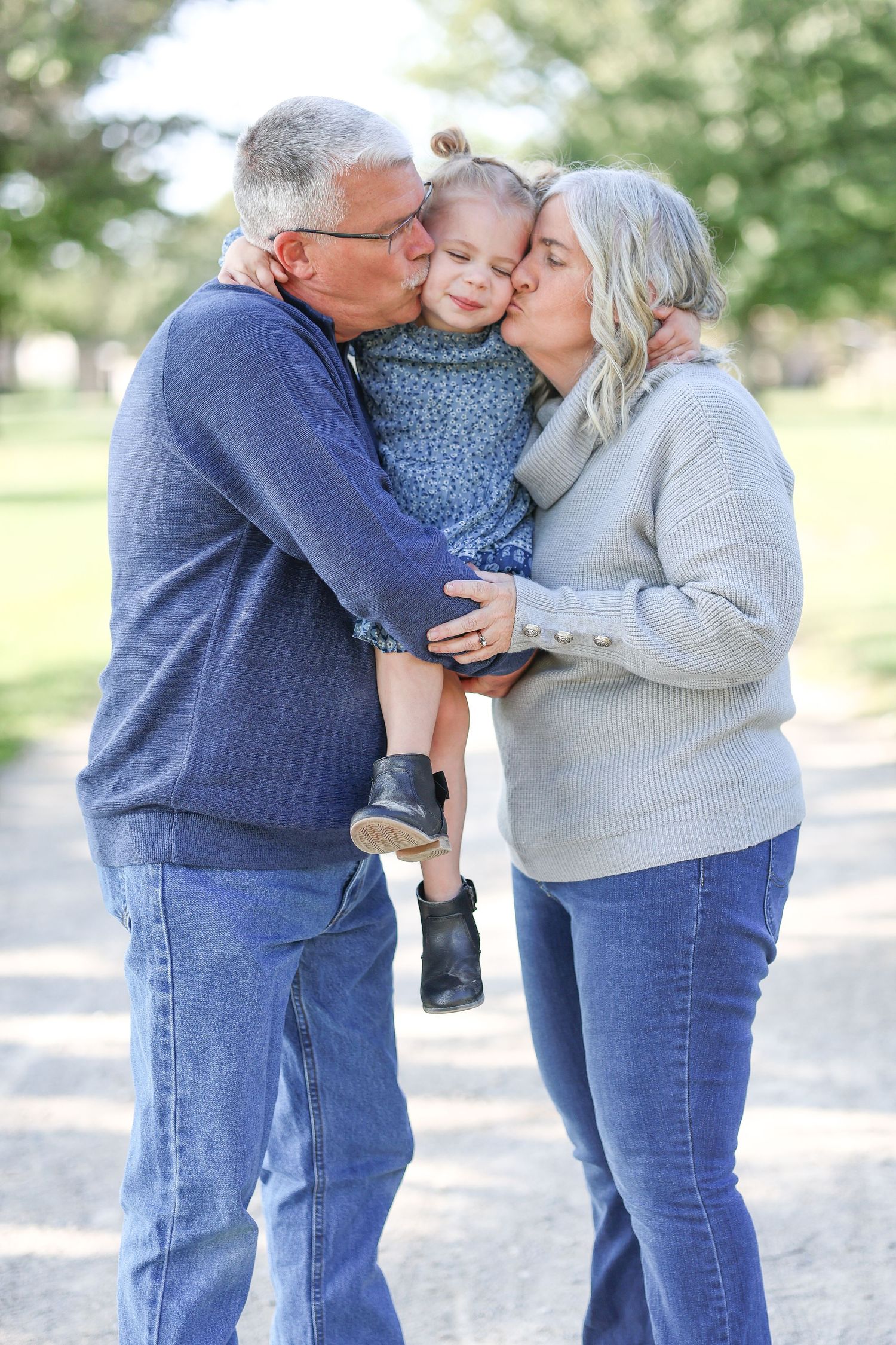 Springfield, IL family photographer captures grandparents kissing their granddaughter's cheeks during a photo session in Central, IL