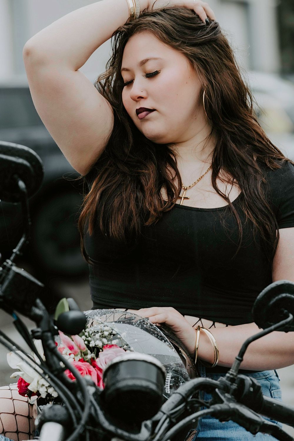 Edgy fashion portrait with a motorcycle and pink flowers against an urban background.