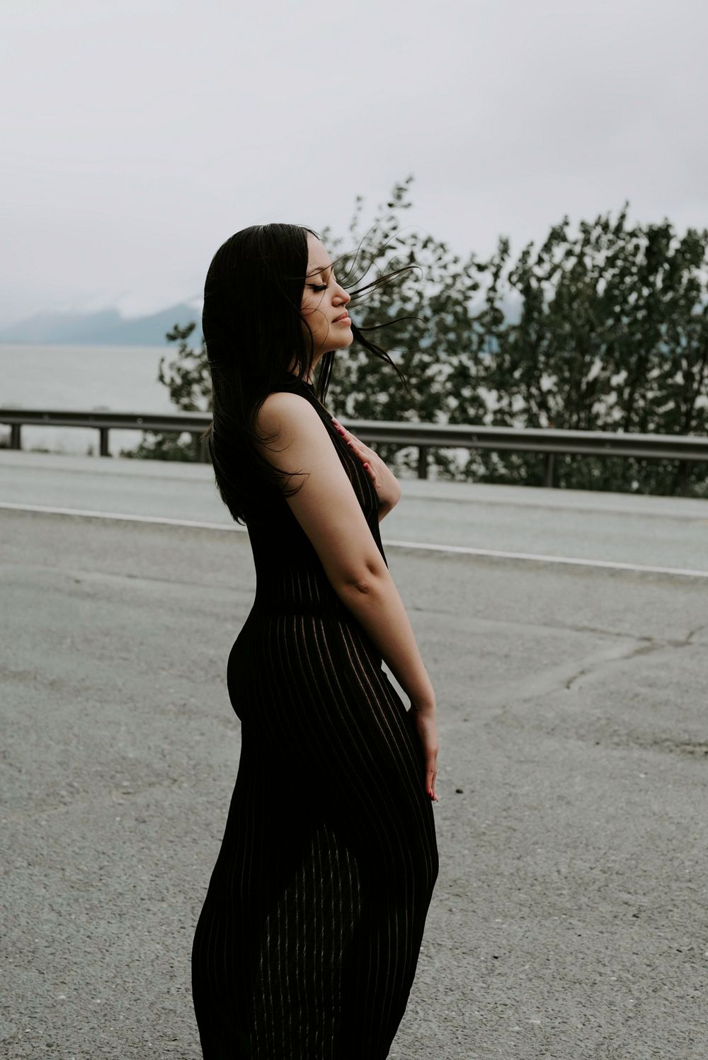 Side profile in black dress against scenic mountain backdrop.