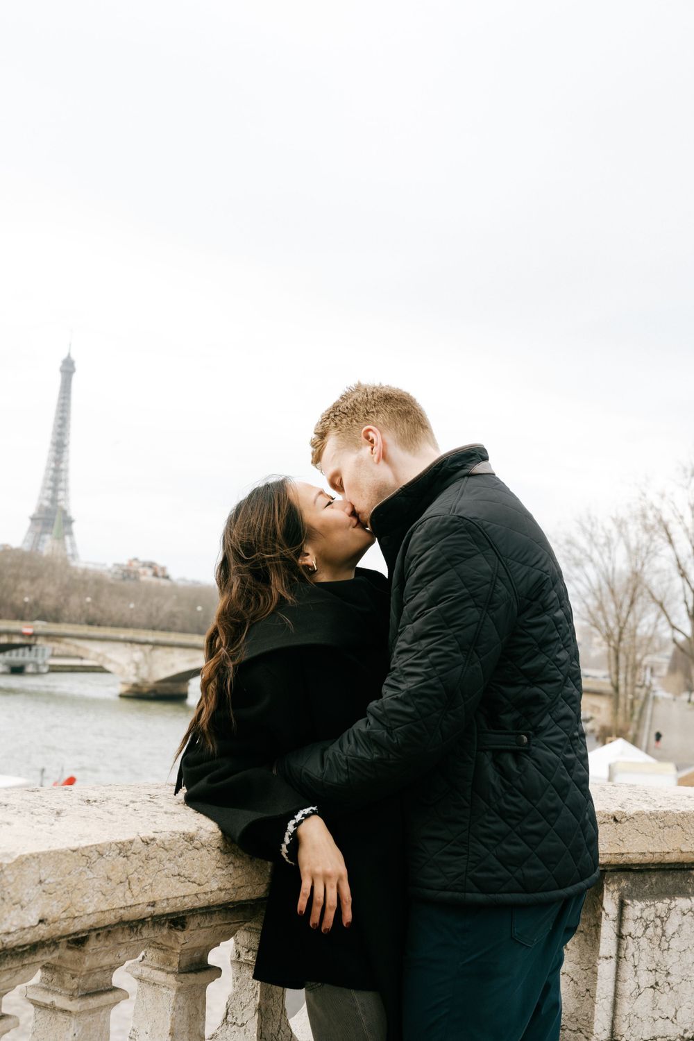 A romantic winter scene in Paris with two people sharing a kiss near the iconic Eiffel Tower. Pont Alexandre III cinematic photoshoot.