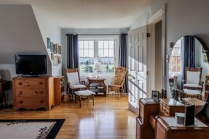 Modern living room interior with hardwood floors, large windows, and minimalist furniture arrangement.