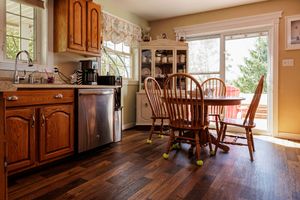 Cozy kitchen with dark hardwood floors, wooden cabinets, and round dining table set by sliding glass doors.