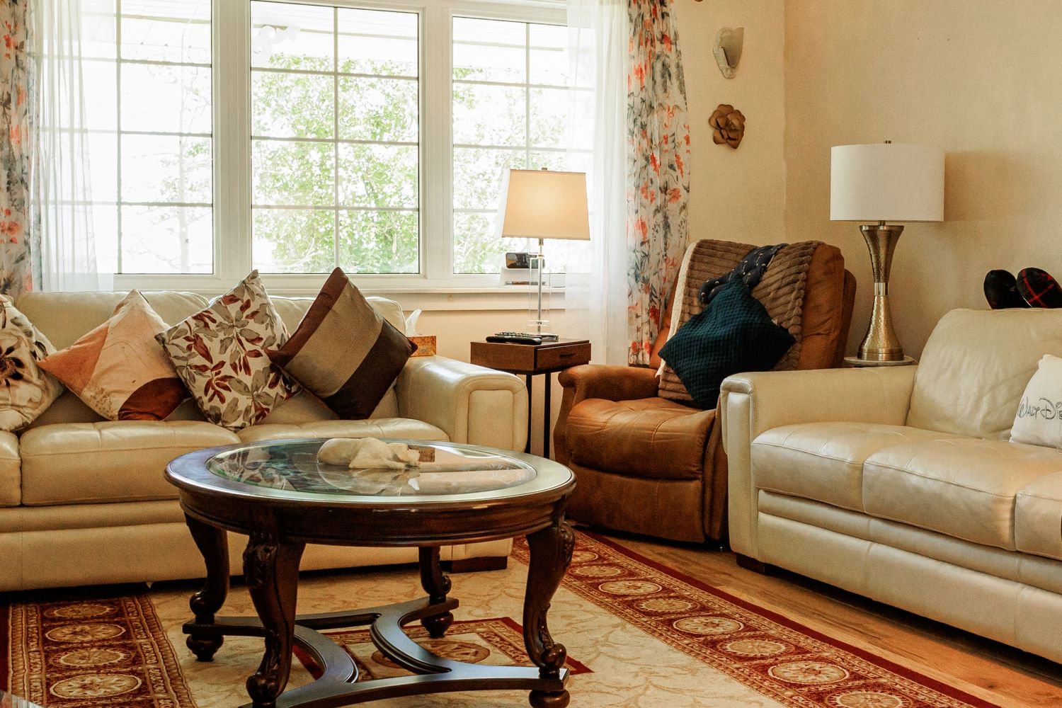 A cozy living room with leather furniture, decorative throw pillows, and a wooden coffee table on a patterned area rug.