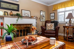 Cozy living room with wooden fireplace, leather armchair, sunflowers, and vintage table lamp creates warm ambiance.