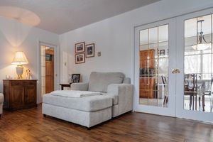 Cozy living room interior with grey chaise lounge, French doors, hardwood floors and warm lighting.