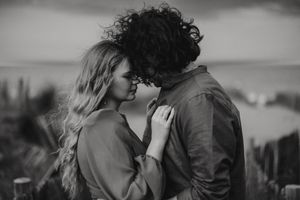 A romantic black and white photo of a couple embracing in an intimate moment against a blurred natural backdrop of Cleethorpes beach.