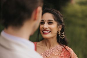 A woman in a traditional Indian dress smiles brightly at her partner during an outdoor photoshoot. Captured by Lincolnshire photographers.