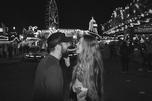 A couple shares an intimate moment at Hull Fair with twinkling lights and rides in the background. Captured by Lincolnshire photographers.