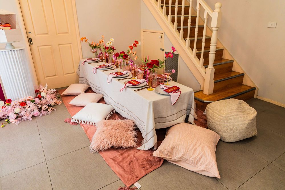 A cozy floor picnic setup with pink cushions and table decorations featuring romantic Valentine's Day decor.