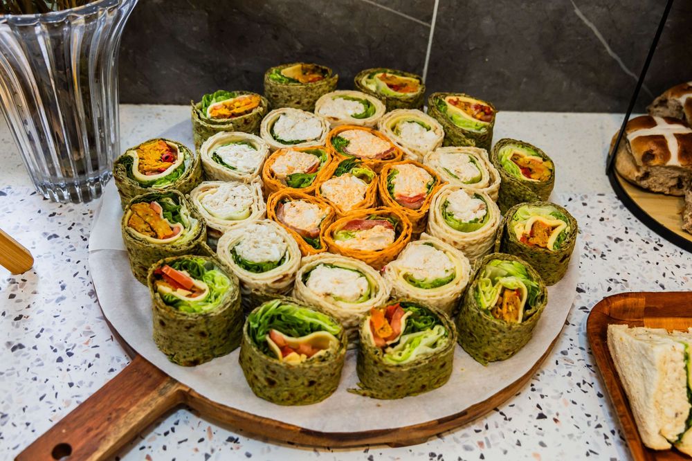 A plate of colorful tortilla pinwheel wraps filled with vegetables and cream cheese arranged in a circular pattern.