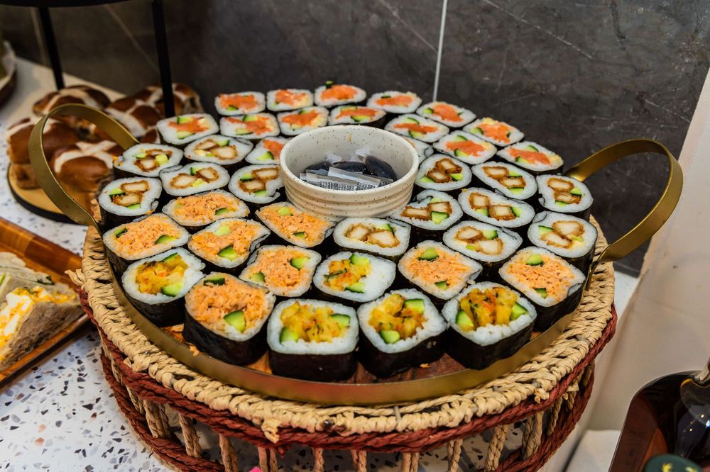 A large platter of homemade sushi rolls arranged in a circular pattern with various colorful fillings and toppings.