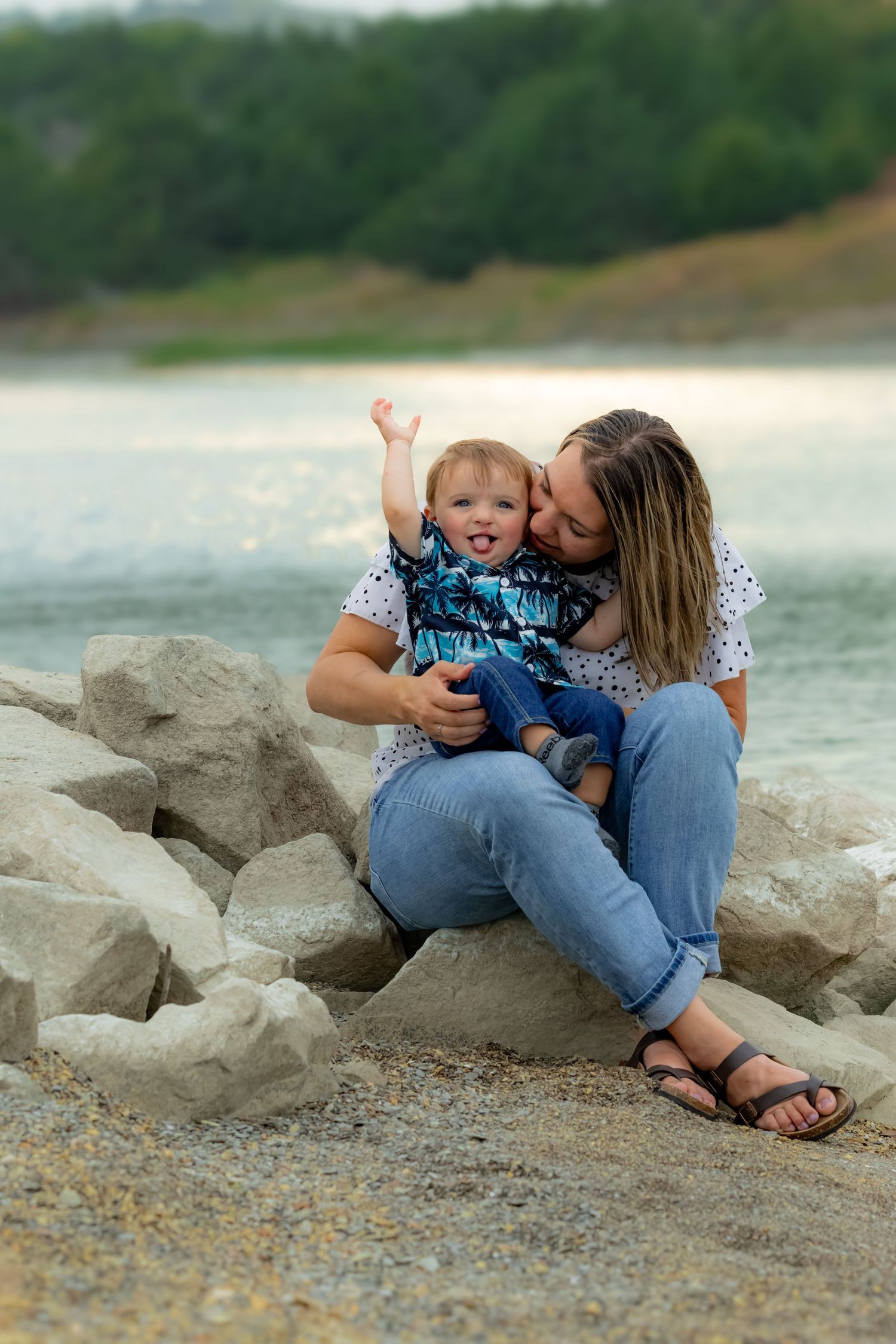 A playful scene unfolds on rocky terrain by a lake with people enjoying each other's company.