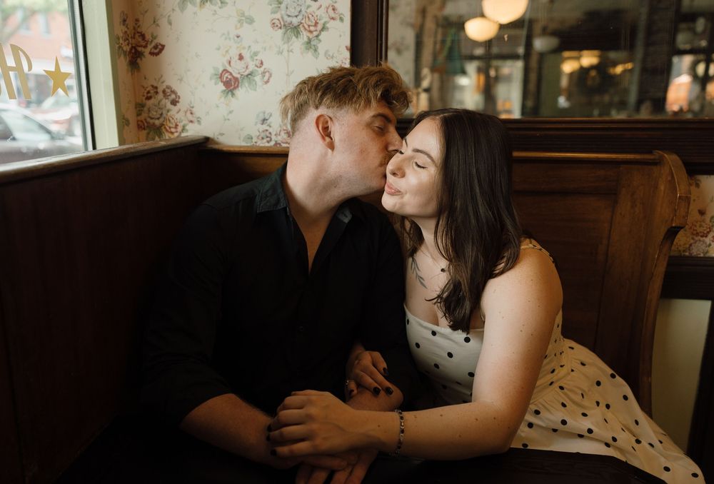 A romantic couple shares an intimate moment in a dimly lit restaurant setting.