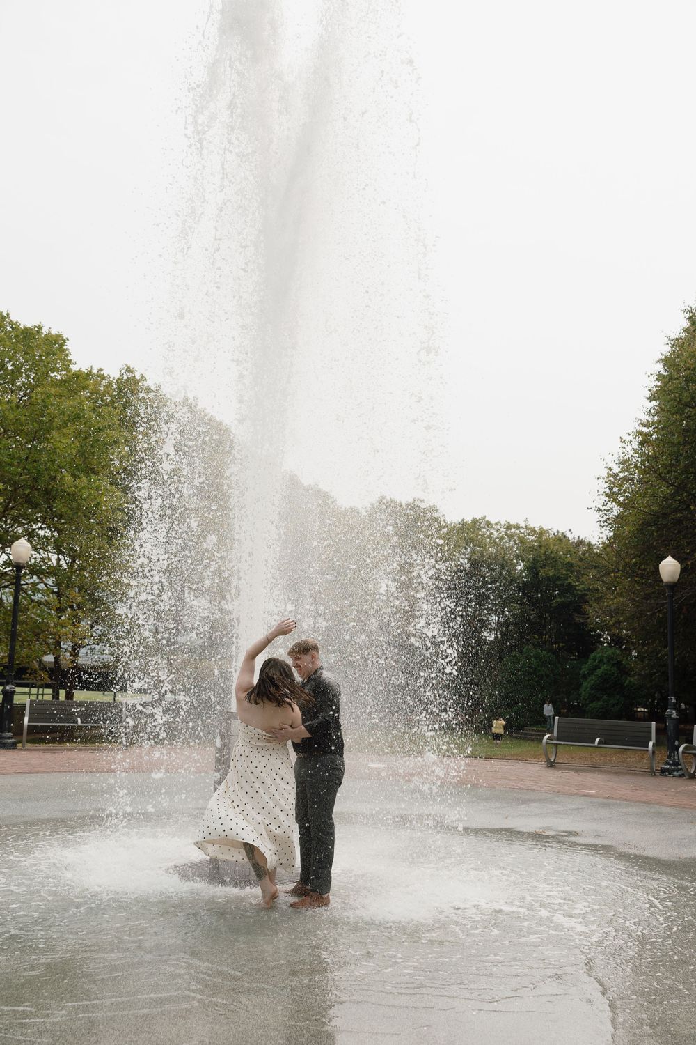 A playful moment captured in front of a dramatic water fountain spray.