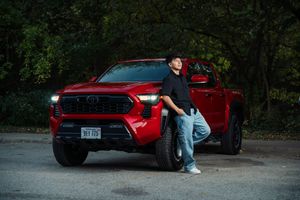 A red Toyota Tacoma truck parked in a wooded area with low light conditions.
