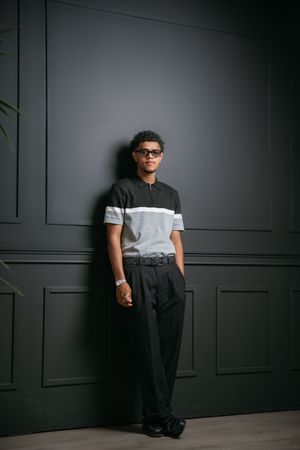Modern studio portrait against dark paneled wall in casual attire.