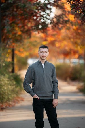 Scenic autumn outdoor photo session with beautiful orange foliage and bokeh lighting effects in the background.
