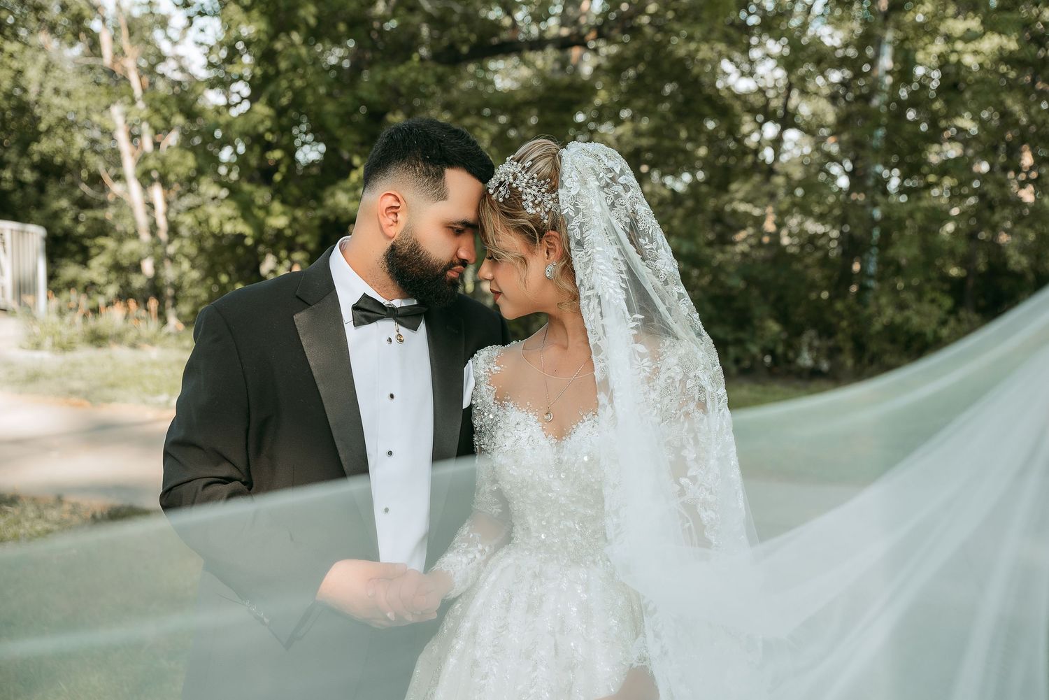 Romantic wedding portrait with flowing veil captured in soft natural lighting.
