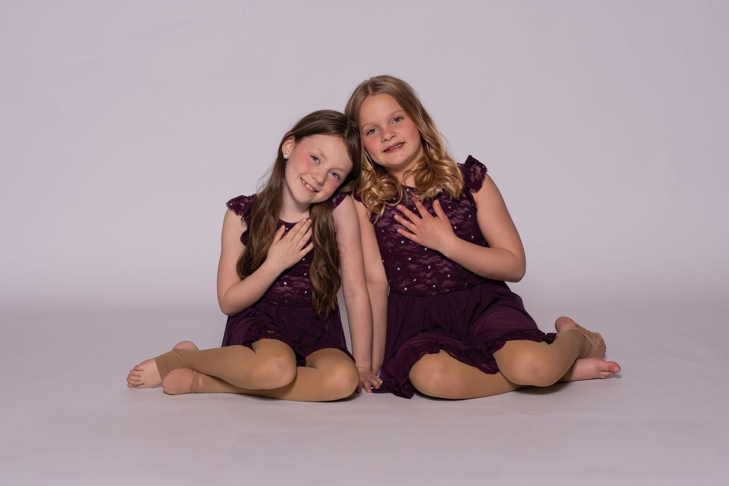 Dance duet captured in artistic poses on studio floor with matching outfits.