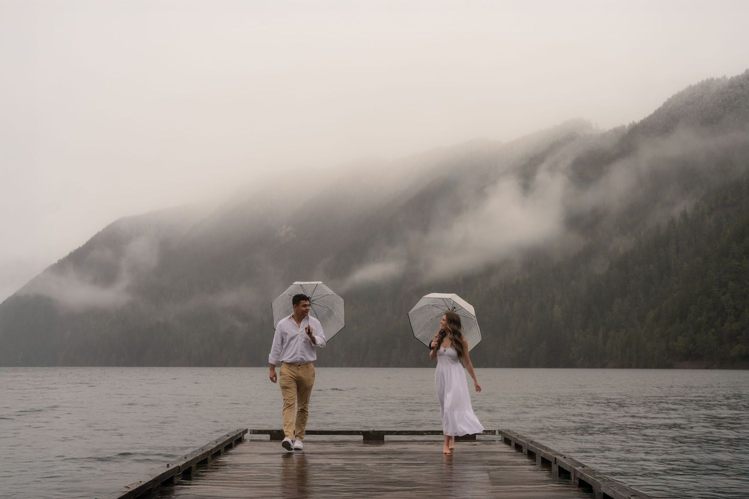 Two figures stand in a mountain meadow filled with white wildflowers at sunset.