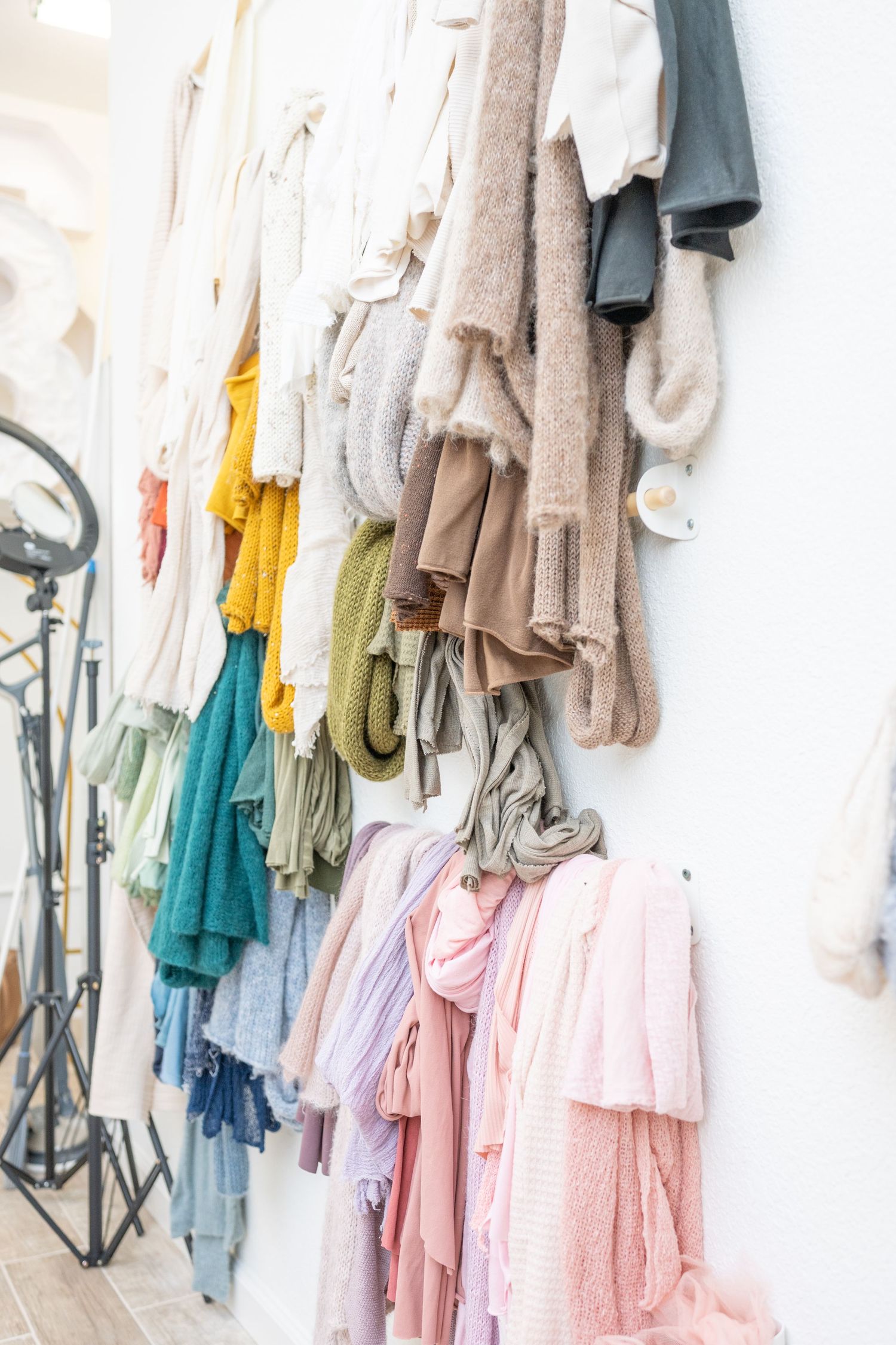 Colorful collection of soft sweaters and garments hanging on white wall mounted racks.