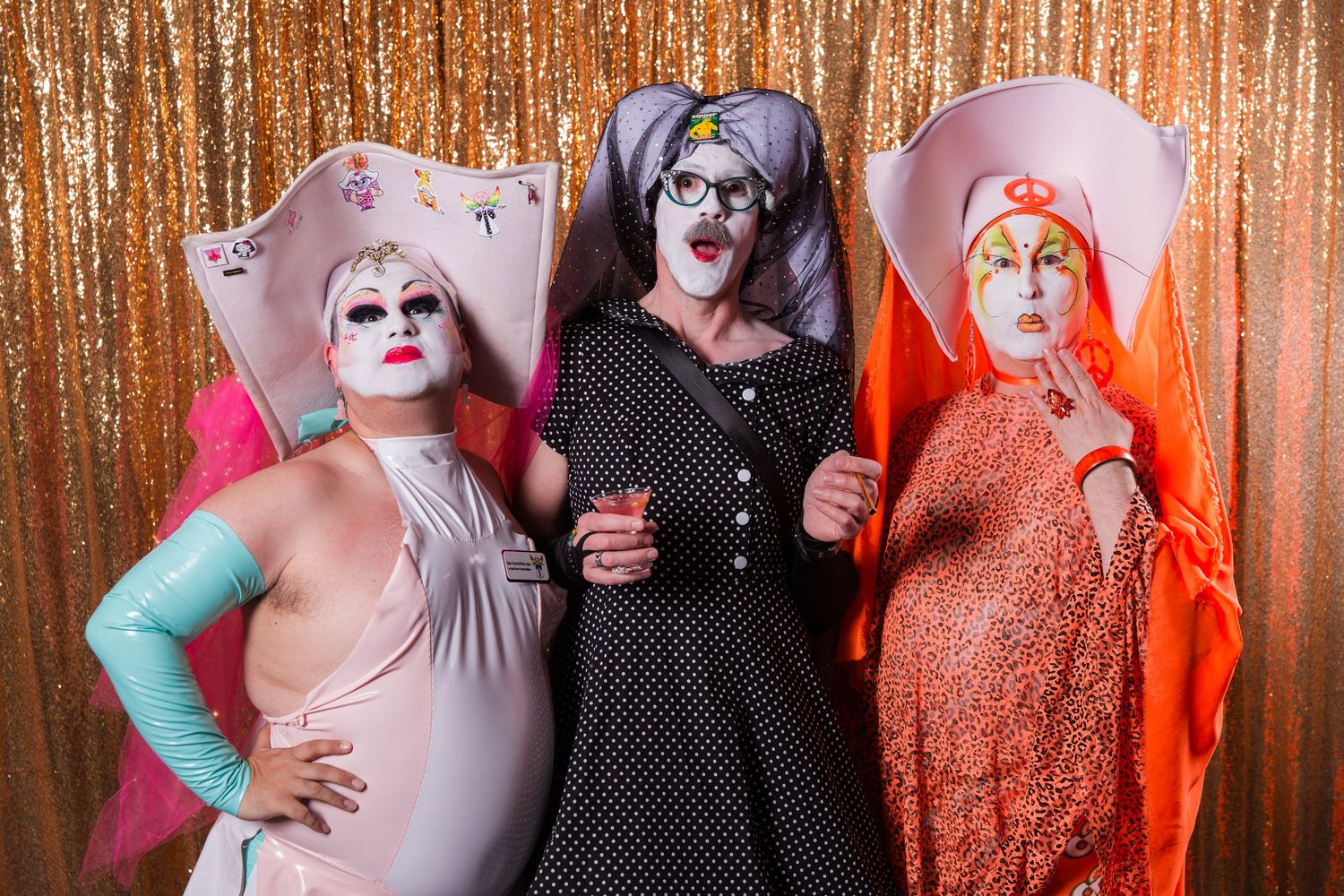 Group photo against a shimmering gold sequin backdrop at an elegant event.
