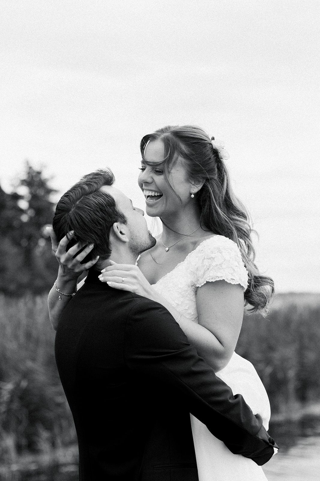 A joyful wedding couple embraces and laughs together in a series of black and white candid outdoor portraits.