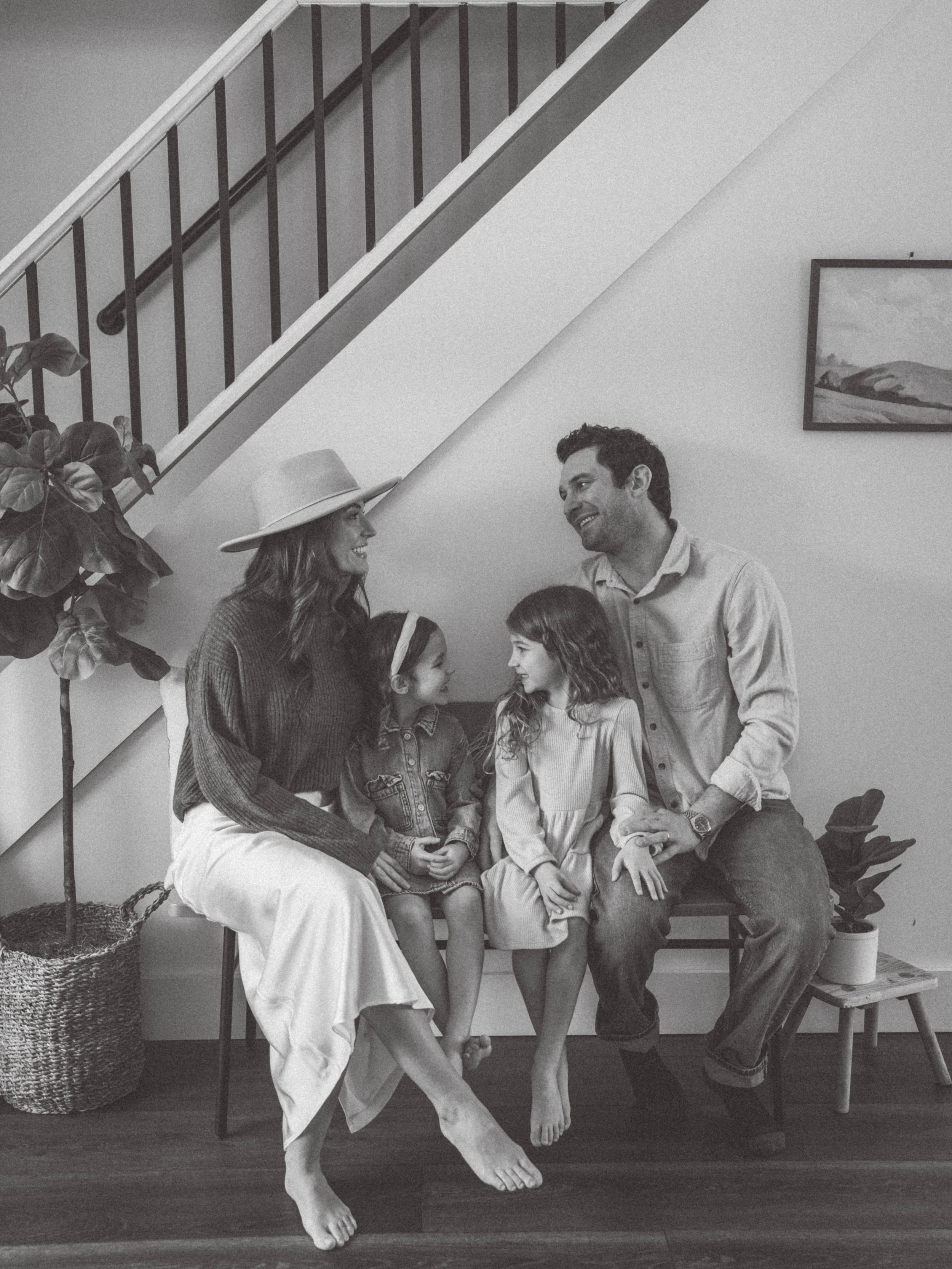 A series of four black and white photos showing people sitting and interacting on stairs in a casual indoor setting.