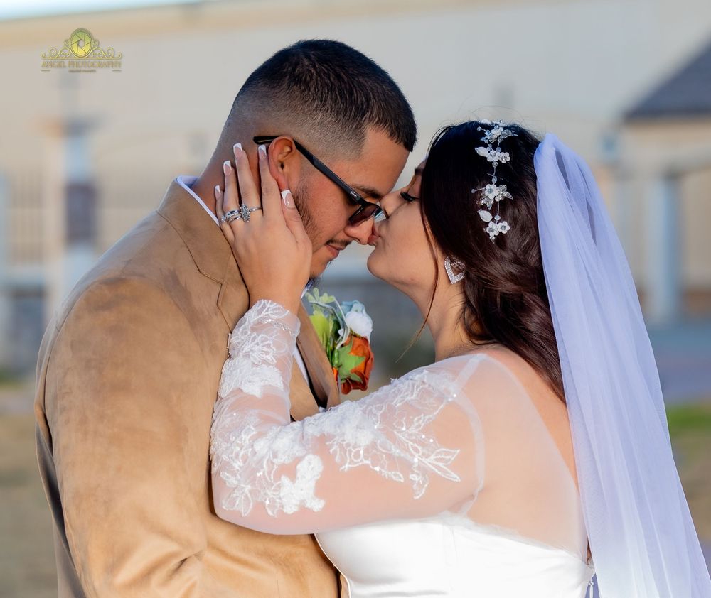 A romantic wedding couple shares a tender kiss against a scenic outdoor background.