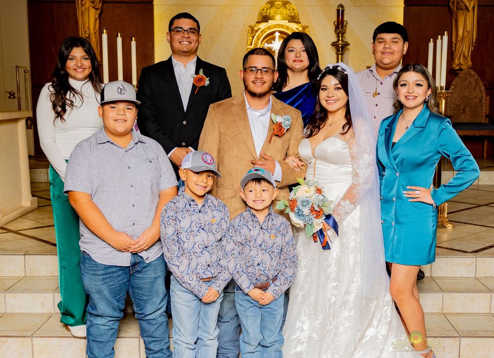 A wedding party poses together at the altar of a church with traditional decorations.