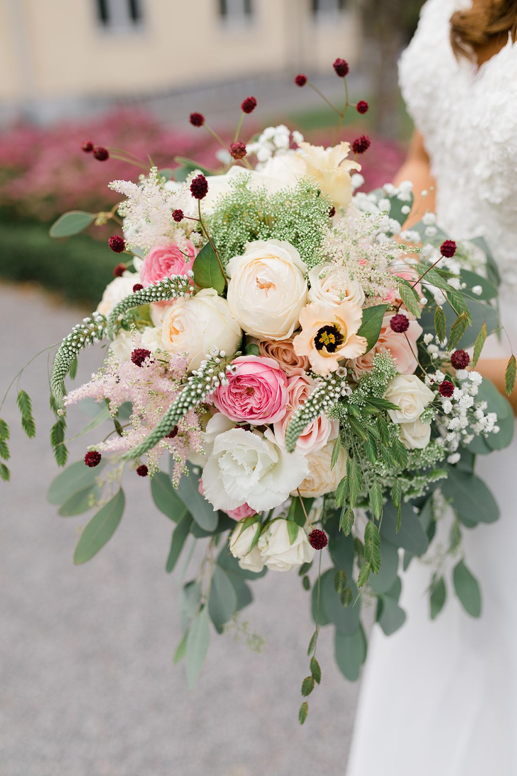 Romantic floral arrangement featuring pink and white roses, anemones, and eucalyptus with burgundy berries for a wedding.