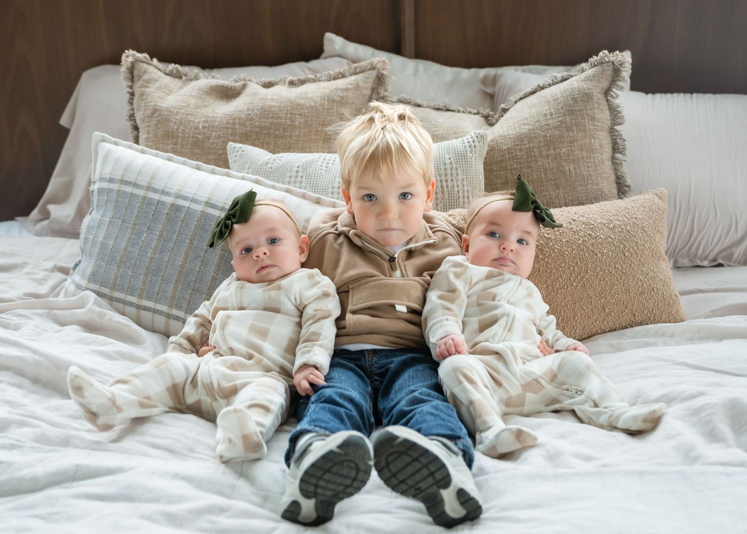 Children lying comfortably on a plush white bed with pillows and blankets.