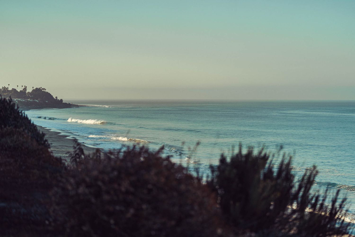 Panoramic ocean view showing gentle waves rolling toward a sandy coastline.